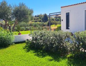 een tuin met een wit huis en een aantal struiken bij Villa secrecy in Lixouri
