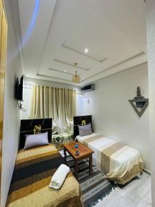 a room with two beds and a table in it at l'habitation avec la famille in Fès