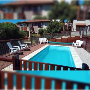 a swimming pool with white chairs at Hotel Tejas Verdes in Villa Gesell