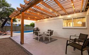 a patio with a table and chairs under a pergola at 3BR Midtown Modern Adobe w Pool & Catalina Views in Tucson