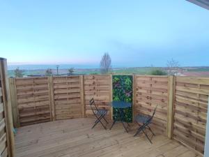 Dos sillas y una mesa en una terraza de madera. en Grand studio, avec terrasse, en Lauzerville