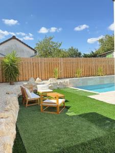 a yard with two chairs and a table next to a pool at Villa Nava in Châtellerault
