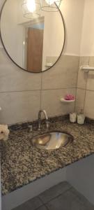 a bathroom sink with a round mirror above it at Casa de 2 dormitorios in Las Varillas