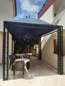 a patio with tables and chairs under a blue umbrella at Le Noflaye in Sali Nianiaral +2 photos