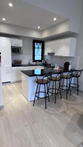 a kitchen with white cabinets and bar stools at Villa Hawana- Salalah in Salalah