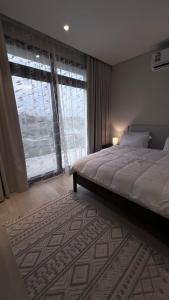 a bedroom with a large bed and a large window at Villa Hawana- Salalah in Salalah
