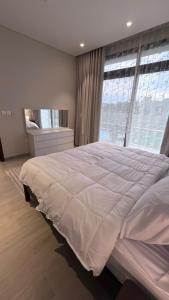 a large bed in a bedroom with a large window at Villa Hawana- Salalah in Salalah