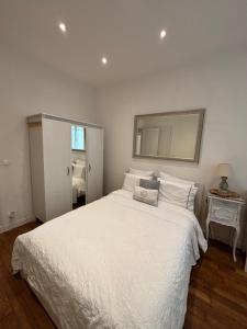 Un dormitorio con una cama blanca y un espejo. en Appart à deux pas de paris expo, en Vanves