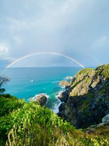 a rainbow over the ocean with a cliff at Tala & Sea in Forster
