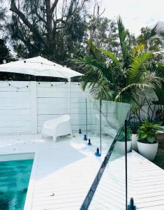 a pool with a white bench and an umbrella at Tala & Sea in Forster