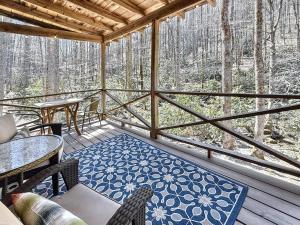 Un porche cubierto con mesas, sillas y árboles. en Karma Cabin, en Scaly Mountain