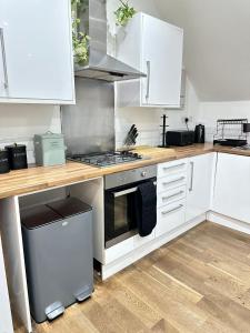a kitchen with white cabinets and a stove top oven at Sky High Apartment in Streatham in London