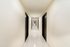 a corridor of a building with black doors and white floors at Super Hotel O CJ Inn in Vijayawada
