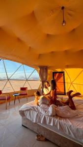ワディ・ラムにあるRUM MOON lUXURY CAMPのテントのベッドに横たわっている女性2人