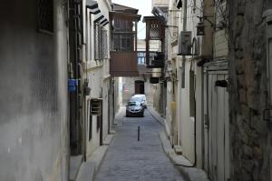 a car driving down a street between two buildings at Double gates home in Baku