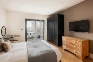 Un dormitorio con una cama, un televisor y una cómoda. en Silver Birches - Eco home, en Holcombe