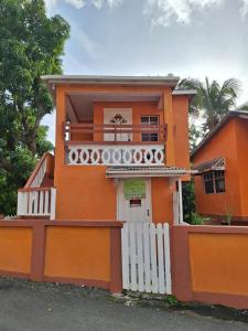 a orange house with a white fence in front of it at EMME Escape in Saint Georgeʼs