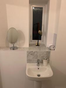 a white bathroom with a sink and a mirror at Fabulous 3 bed house close to Lakeside shopping Centre in West Thurrock