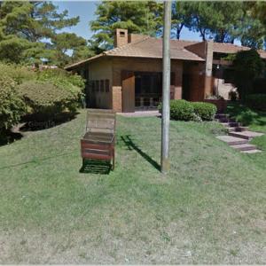 two benches sitting in the grass in front of a house at Hotel Tejas Verdes in Villa Gesell