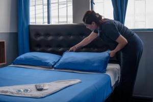 a woman putting pillows on top of a bed at Hotel Bogotá Airport in Bogotá