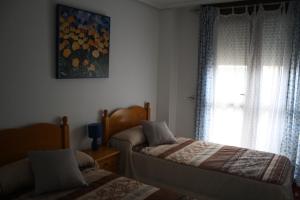 1 dormitorio con 2 camas y ventana en Apartamento de Playa Somo Loredo en Loredo