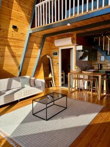a living room with a glass coffee table on a rug at Mugada Deluxe Bungalov in Güzelcehisar