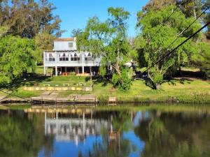 a large white house sitting on the side of a lake at Escapada ideal privada y cerca del Rio Con todo in Aguas Corrientes