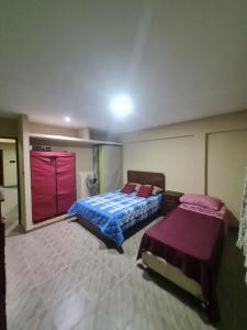 a bedroom with two beds and a red door at Hospedaje Temporal del Alto in San Salvador de Jujuy