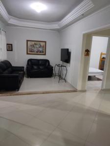 sala de estar con sofás de cuero negro y TV en Casas para Temporada RS, en Praia Grande 22 fotos más