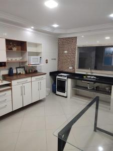 cocina grande con armarios y electrodomésticos blancos en Casas para Temporada RS, en Praia Grande