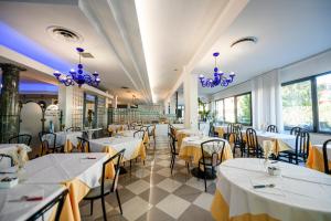 a restaurant with white tables and chairs and purple chandeliers at hotel falco azzurro in Martinsicuro