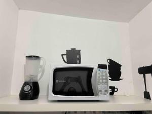 a microwave sitting on a shelf next to a blender at Studio Pandora in Capim Macio in Natal