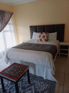 1 dormitorio con 1 cama grande y mesa en Princess Spa & Lodge, en Pretoria 7 fotos más