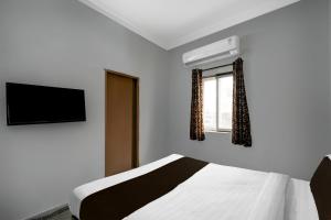 a bedroom with a bed and a television and a window at Hotel O Shamshabad Station Formerly Grand Vista Hotel in Shamshabad
