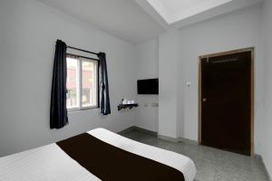 a bedroom with a bed and a window and a door at Hotel O Shamshabad Station Formerly Grand Vista Hotel in Shamshabad