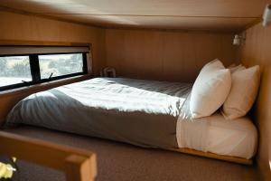 a large bed in a small room with a window at Hahei Tiny Home - Outdoor Bath in Hahei