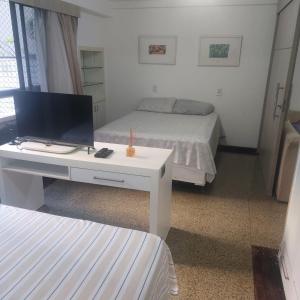 a room with two beds and a desk with a television at Residence Scala in Fortaleza