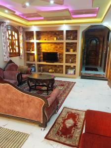 a living room with couches and a table and a tv at Nagar Villa For Rent in Luxor