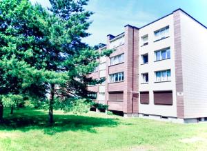 un edificio con un árbol delante en M&M Apartment I near Panevezys, en Velžys