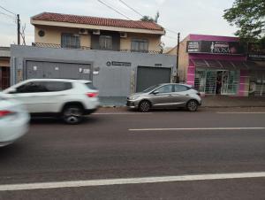 two cars driving down a street next to a building at Espaço Ideal 1 com 2 Quartos in Cascavel