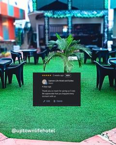 a sign on a lawn with chairs and a plant at Uptown Life Hotel and Suites in Warri +5 photos