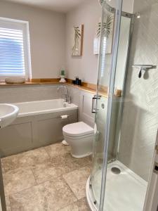 a bathroom with a shower and a toilet and a sink at Boutique Burnham Market Cottage in Burnham Market