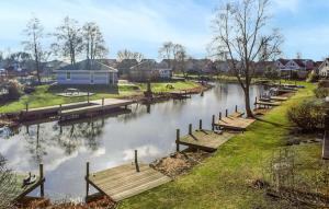 Un río con varios bancos de madera y una casa. en Nice Home In Makkum With Lake View, en Holle Poarte