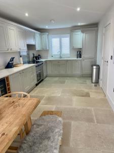 a kitchen with white cabinets and a wooden table at Boutique Burnham Market Cottage in Burnham Market +9 photos