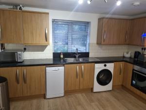 a kitchen with wooden cabinets and a washer and dryer at Spacious 3BR Home with Large Garden - Ashford, Kent in Kennington +17 photos
