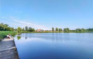 a man sitting on a dock next to a lake at 2 Bedroom Cozy Home In Heinkenszand in Graszode
