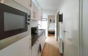 a kitchen with white cabinets and a tv on the wall at 2 Bedroom Cozy Home In Heinkenszand in Graszode