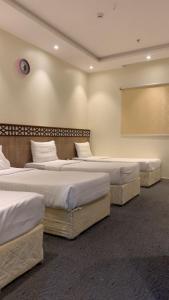 three beds in a room with a projection screen at فندق شركة وردة الوادي توصيل من والي الحرم 24 مجاني in An Naqāʼ +8 photos