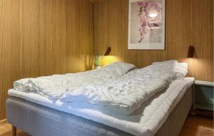 a large white bed in a room with wood walls at Amazing Home In Aakirkeby With Wifi in Boderne
