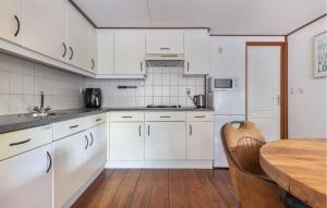 Una cocina con gabinetes blancos y una mesa de madera. en Cozy Home In Erm With Private Swimming Pool, Can Be Inside Or Outside, en Erm